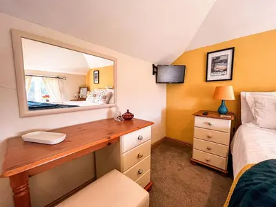 a bedroom with a desk with a mirror and a bed at Tramways Holiday Cottage in Carnbrea