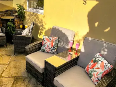 two wicker chairs and a table on a patio at Tramways Holiday Cottage in Carnbrea