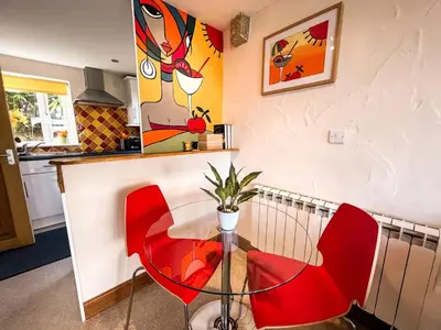 a dining room with red chairs and a table at Tramways Holiday Cottage in Carnbrea