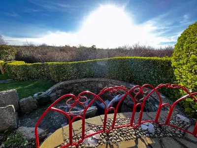 a fire pit in a garden with red metal fences at Tramways Holiday Cottage in Carnbrea