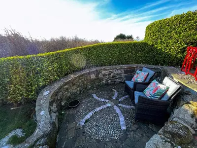 a couch sitting in front of a hedge at Tramways Holiday Cottage in Carnbrea