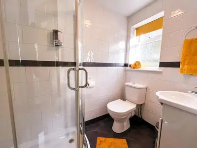 a bathroom with a shower and a toilet and a sink at Tramways Holiday Cottage in Carnbrea