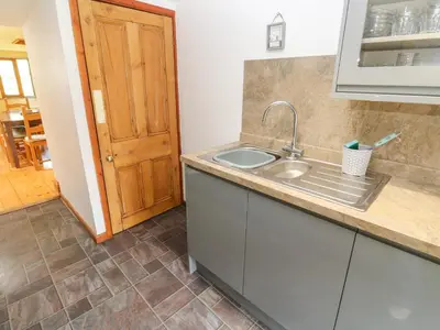 a kitchen with a sink and a wooden door at The Cottage in St Ives