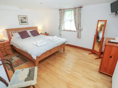 a bedroom with a bed and a wooden floor at The Cottage in St Ives