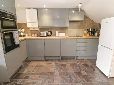 a kitchen with white cabinets and a tile floor at The Cottage in St Ives