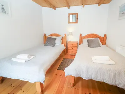 two twin beds in a room with wooden floors at The Cottage in St Ives