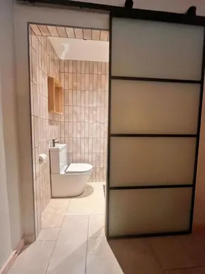 a bathroom with a toilet through a sliding door at Treth Newquay in Newquay