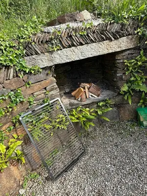 a stone fireplace with a cage on top of it at Static Caravan Near Perranporth in Perranporth