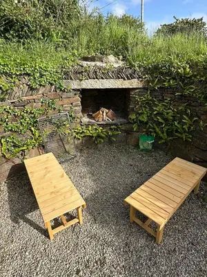 two wooden benches and a fireplace in front of a wall at Static Caravan Near Perranporth in Perranporth