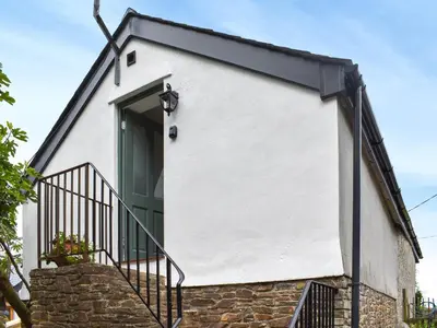 a white house with a green door and stairs at Roseland Roost - Uk49839 in Truro