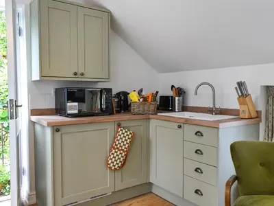 a kitchen with white cabinets and a sink at Roseland Roost - Uk49839 in Truro