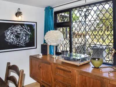 a wooden dresser with a vase on it with a window at Rivendell Cottage in Liskeard