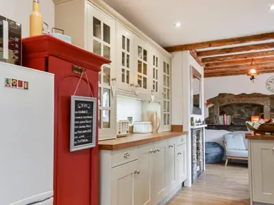 a kitchen with white cabinets and a red refrigerator at Rivendell Cottage in Liskeard