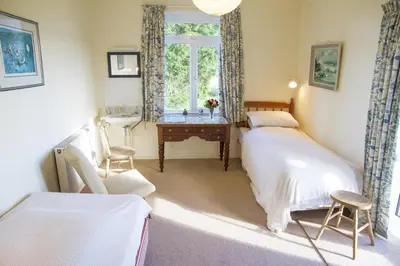 a bedroom with two beds and a desk and a window at Wesdale Holiday Home in Polzeath