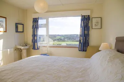 a bedroom with a large bed and a window at Wesdale Holiday Home in Polzeath