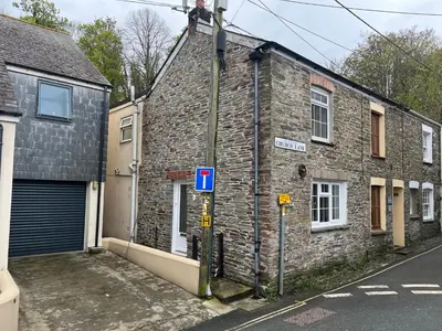 an old brick building on a street with a garage at Maureen's Cottage in Padstow