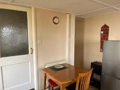 a kitchen with a table and a clock on the wall at Maureen's Cottage in Padstow
