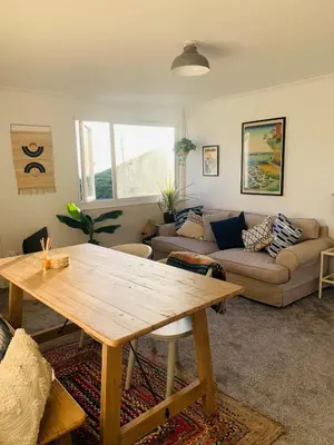 a living room with a wooden table and a couch at Lovely two bed flat with a sea view next to beach in Porthtowan