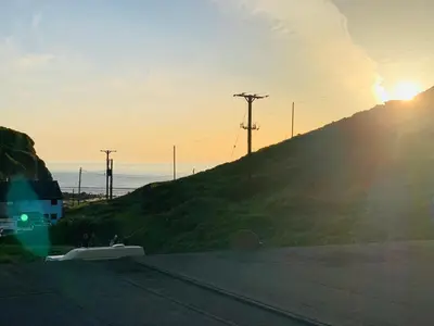 a sunset over a hill with the sun shining on a hill at Lovely two bed flat with a sea view next to beach in Porthtowan