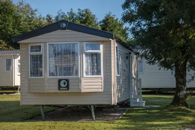 a tiny house sitting in a yard next to a tree at Trevarth Holiday Park in Chacewater