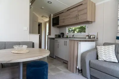 a kitchen and living room with a table and a couch at Trevarth Holiday Park in Chacewater
