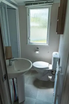 a bathroom with a toilet and a sink and a window at Trevarth Holiday Park in Chacewater