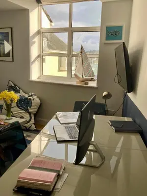 a living room with a glass table with a laptop on it at 'Shorebird' central apartment, sea views & parking in Falmouth