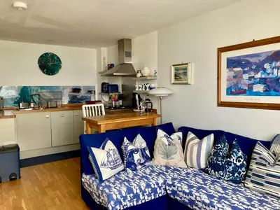 a living room with a blue couch with pillows at 'Shorebird' central apartment, sea views & parking in Falmouth