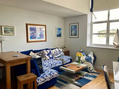 a living room with a blue couch and a table at 'Shorebird' central apartment, sea views & parking in Falmouth