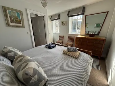 a bedroom with a bed and a dresser and a mirror at 'Shorebird' central apartment, sea views & parking in Falmouth