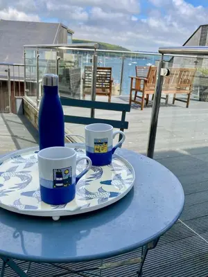 a blue table with two cups and a blue bottle at 'Shorebird' central apartment, sea views & parking in Falmouth
