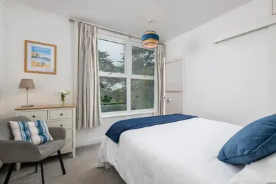 a bedroom with a bed and a chair and a window at Penstraze cottage near Gylly Beach in Falmouth