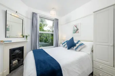 a white bedroom with a bed and a fireplace at Penstraze cottage near Gylly Beach in Falmouth