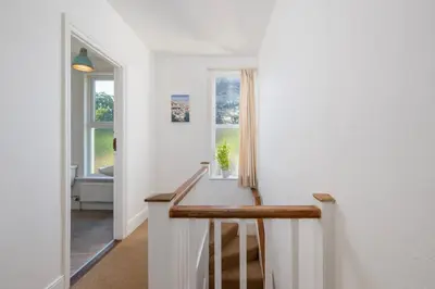 a hallway with white walls and a staircase with a window at Penstraze cottage near Gylly Beach in Falmouth