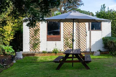 a picnic table with an umbrella in a yard at Penstraze cottage near Gylly Beach in Falmouth