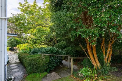 a garden with a tree and a stone path at Penstraze cottage near Gylly Beach in Falmouth