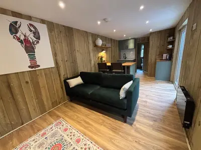 a living room with a green couch and a table at Cornish wooden cabin & wood fired hot tub in Gwennap