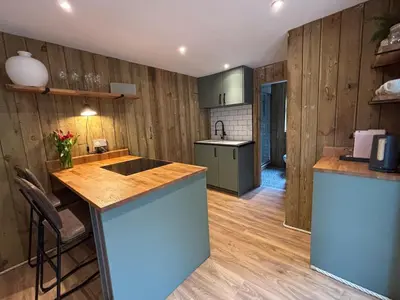 a kitchen with wooden walls and a island in a room at Cornish wooden cabin & wood fired hot tub in Gwennap