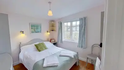 a bedroom with a white bed and a window at C14 Gwelmore, Riviere Towans in Hayle