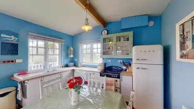 a kitchen with blue walls and a white refrigerator at C14 Gwelmore, Riviere Towans in Hayle