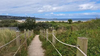 a path leading to a beach with a fence at C14 Gwelmore, Riviere Towans in Hayle