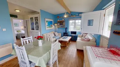 a dining room with a table and a living room at C14 Gwelmore, Riviere Towans in Hayle