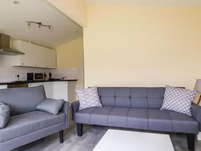 a living room with two couches and a kitchen at H2 Atlantic Bay Holiday Park in Padstow