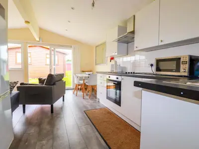 a kitchen with white cabinets and a living room at H2 Atlantic Bay Holiday Park in Padstow