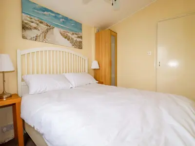a bedroom with a white bed and a painting on the wall at H2 Atlantic Bay Holiday Park in Padstow