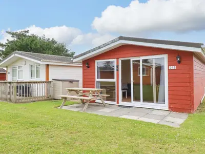 a red shed with a picnic table in a yard at 161 Atlantic Bay Holiday Park in Padstow