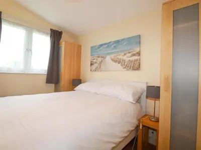 a bedroom with a white bed and a window at 161 Atlantic Bay Holiday Park in Padstow