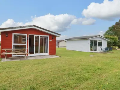 a small red and white house with a yard at 161 Atlantic Bay Holiday Park in Padstow