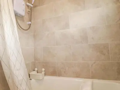 a bathroom with a shower and a white tub at 161 Atlantic Bay Holiday Park in Padstow
