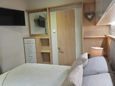 a bedroom with a bed and a door with a television at Newquay Bay Resort - Poppy's Lodge Retreat in Newquay